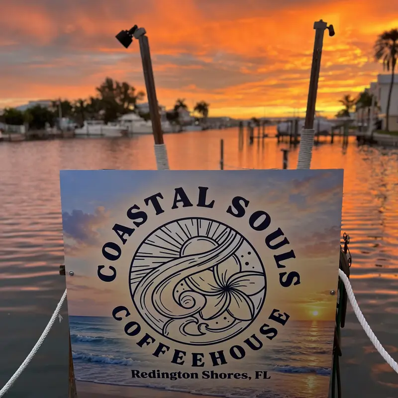 The Coastal Souls Coffeehouse sign by the water, morning sky over the marina