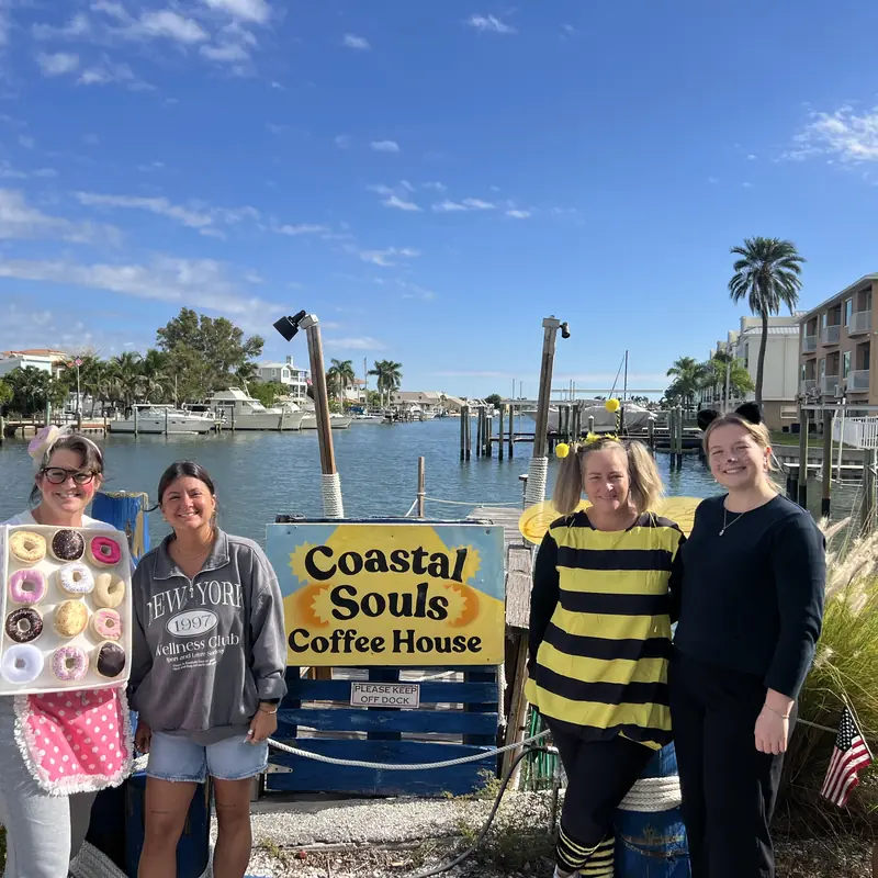 Guests in costumes by the Coastal Souls sign at the marina