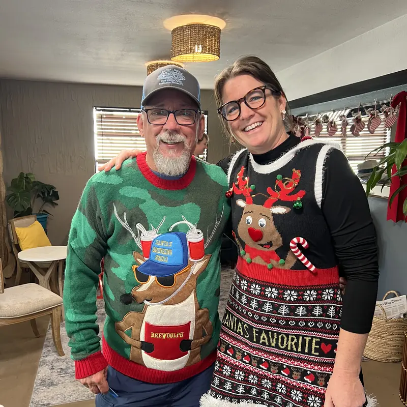 Two guests in holiday sweaters inside the shop