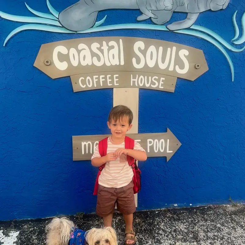 The painted Coastal Souls Coffee House wall, with a young guest and a small dog in front