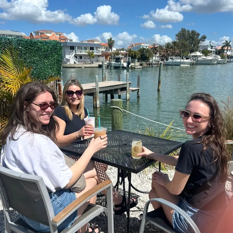Guests with iced drinks on the patio by the water